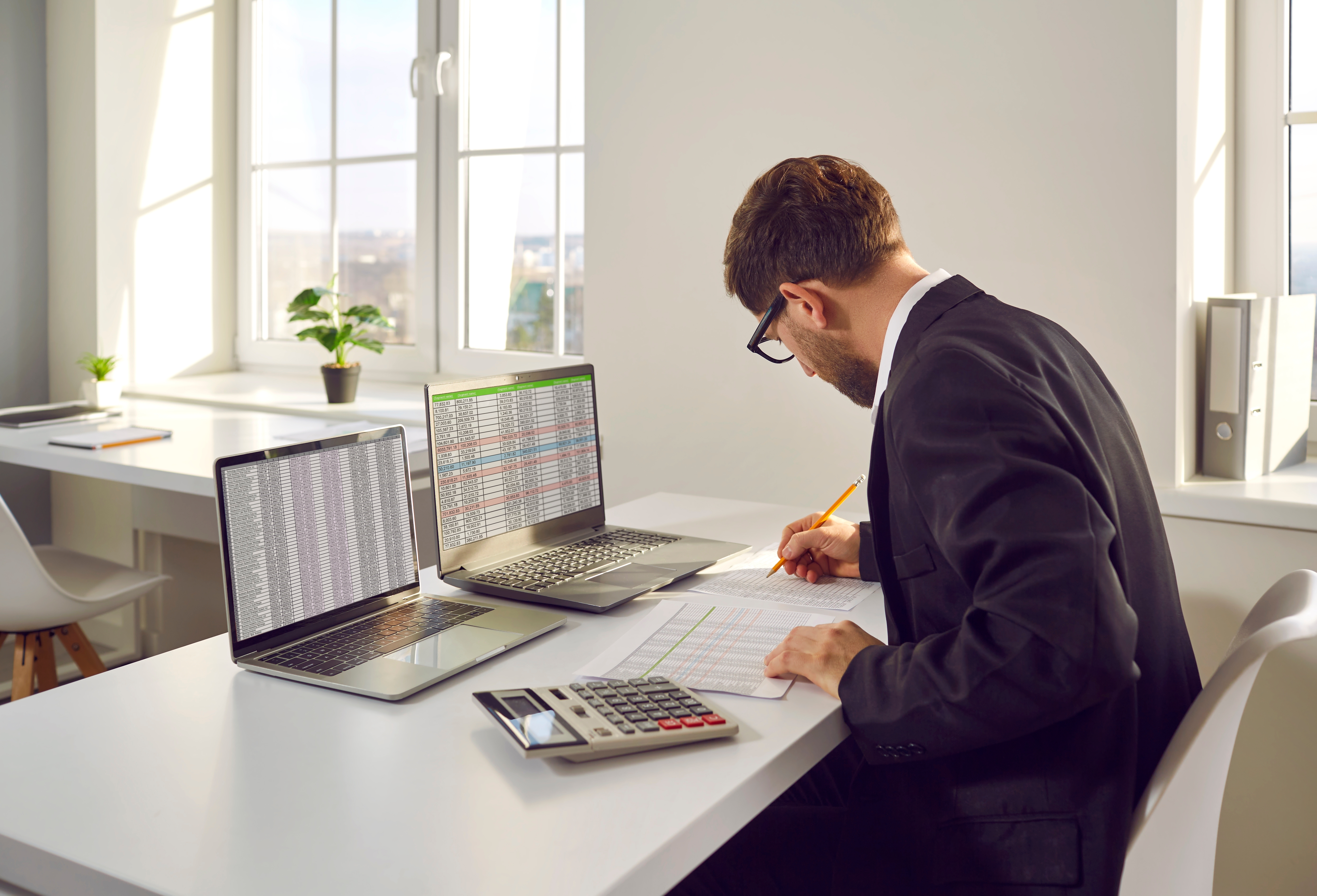 A man reviewing documents and taking notes at an office desk