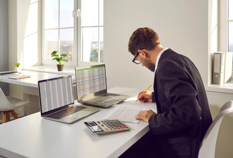 A man reviewing documents and taking notes at an office desk